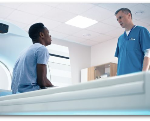Male Radiographer standing over a male patient about to have an MRI for men's health